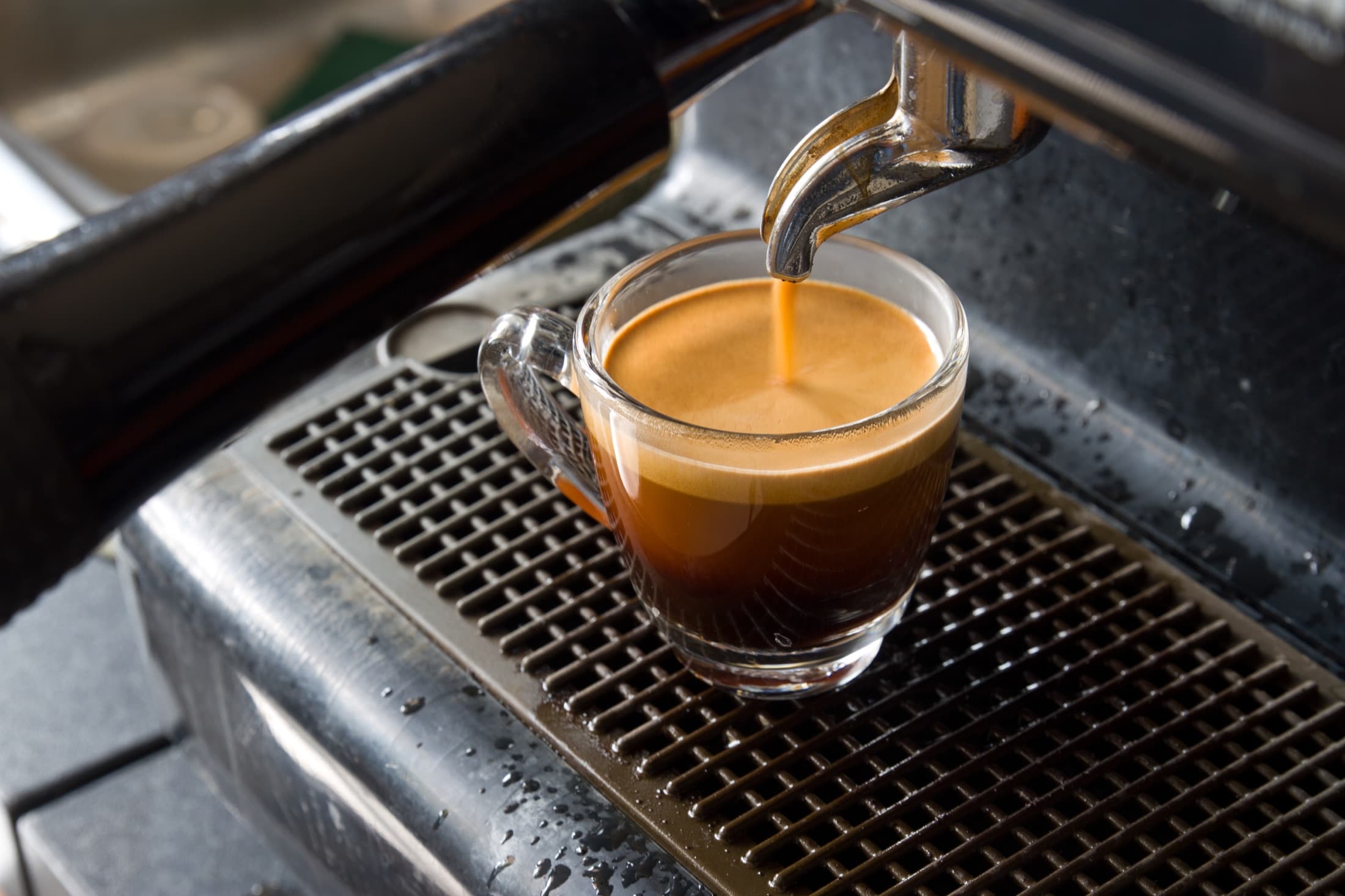 Espresso pouring from a machine into a glass cup